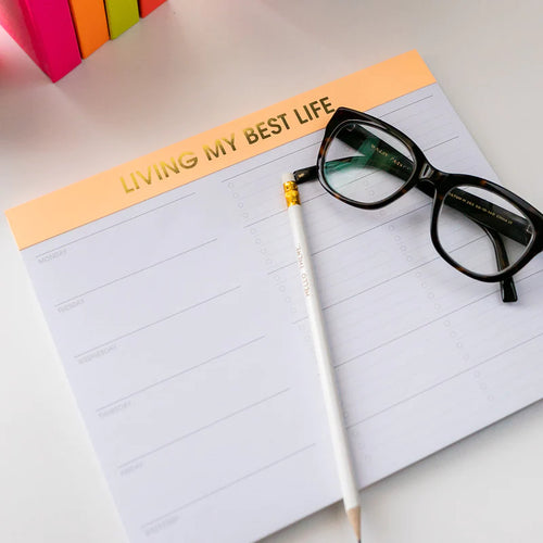 photo of "living my best life" planner on desk with glasses and pencil